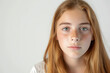 Serene teenage girl with freckles and striking green eyes against a clean white background.