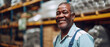 A warehouse worker with a genial smile suggests satisfaction in a job well done, amidst aisles of goods