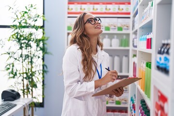 Canvas Print - Young beautiful hispanic woman pharmacist writing on document at pharmacy