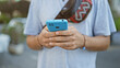 © Krakenimages.com - A young hispanic man with a beard uses a smartphone on a busy city street.