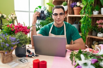 Sticker - Young hispanic man florist holding professional camera using laptop at flower shop