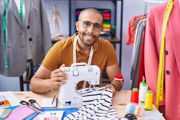 Poster - Young latin man tailor smiling confident using sewing machine at atelier