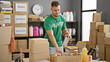 A focused man, classified as latino, volunteers at a warehouse sorting canned goods for donations amid cardboard boxes.