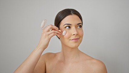 Poster - Young beautiful hispanic woman smiling confident massaging face using skin gym over isolated white background