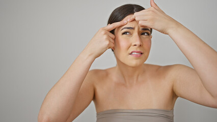 Wall Mural - Young beautiful hispanic woman popping pimple over isolated white background