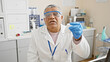 © Krakenimages.com - Mature grey-haired man in lab coat and gloves analyzing a sample in a laboratory setting, portraying healthcare and scientific research themes.