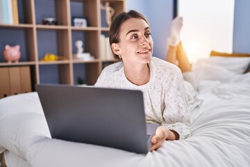 Sticker - Young caucasian woman using laptop lying on bed at bedroom