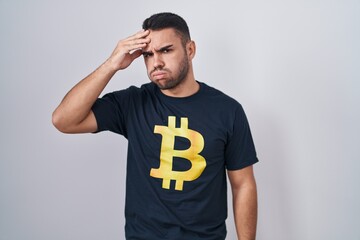 Canvas Print - Young hispanic man wearing bitcoin t shirt worried and stressed about a problem with hand on forehead, nervous and anxious for crisis