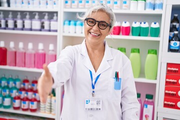 Canvas Print - Middle age grey-haired woman pharmacist smiling confident shake hand at pharmacy