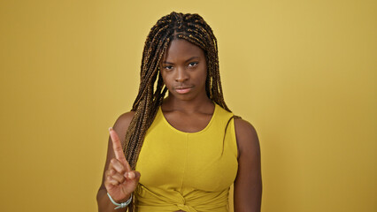 Poster - African american woman standing with serious expression saying no with finger over isolated yellow background