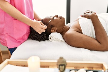 Poster - African american woman lying on massage table having eyebrows treatment at beauty salon