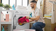 © Krakenimages.com - Young hispanic man washing clothes at laundry room