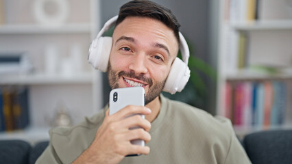 Canvas Print - Young hispanic man listening to music singing song at home