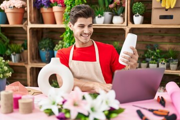 Sticker - Young hispanic man florist using laptop holding pot at flower shop