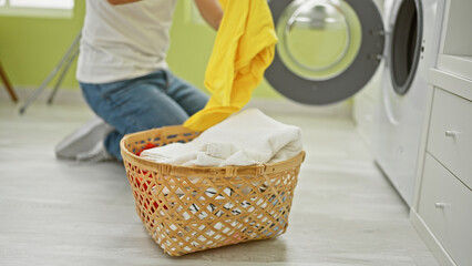 Wall Mural - A young man kneeling while doing laundry in a brightly lit room, adding vibrancy and a domestic touch.