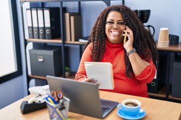 Poster - African american woman business worker talking on smartphone reading notebook at office