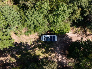 Wall Mural - Caravan with solar panels on roof camp on nature. Aerial view.