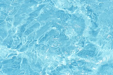 Water surface. Bluewater waves on the surface ripples blurred. Defocus blurred transparent blue colored clear calm water surface texture with splash and bubbles. Water waves with shining pattern.