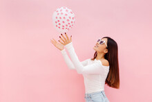 Beautiful Asian Woman In Eyeglasses Playing With Balloon While Posing Isolated