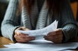 © tonstock - In a cozy setting, a person is engrossed in reviewing documents, possibly sorting through important paperwork or preparing for a busy day ahead.