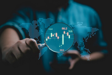 Wall Mural - Businessman holding magnifier glass with stock market graph chart for focus and analysis stock market price , trader use technology invest and value investment concept.