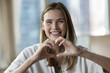 © fizkes - Head shot close up portrait happy woman showing heart symbol gesture with fingers, make love sign, express sincere feelings, looks at camera. E-dating services, donation campaign, loyalty, I Love You