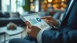 © akarawit - Businessman using a tablet in hand with analyzing financial statistics displayed on the tablet screen