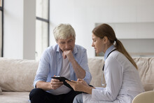 Serious Doctor Woman In White Coat Giving Treatment Recommendation To Older Man, Explaining Medical Checkup Results, Diagnosis, Therapy Instructions, Meeting With Patient At Home