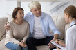 © fizkes - Serious concerned old retired couple consulting family doctor, talking to practitioner at home, getting medical examination, checkup result, listening to treatment recommendation