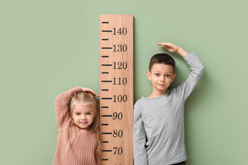 Wall Mural - Cute little children measuring height on green background