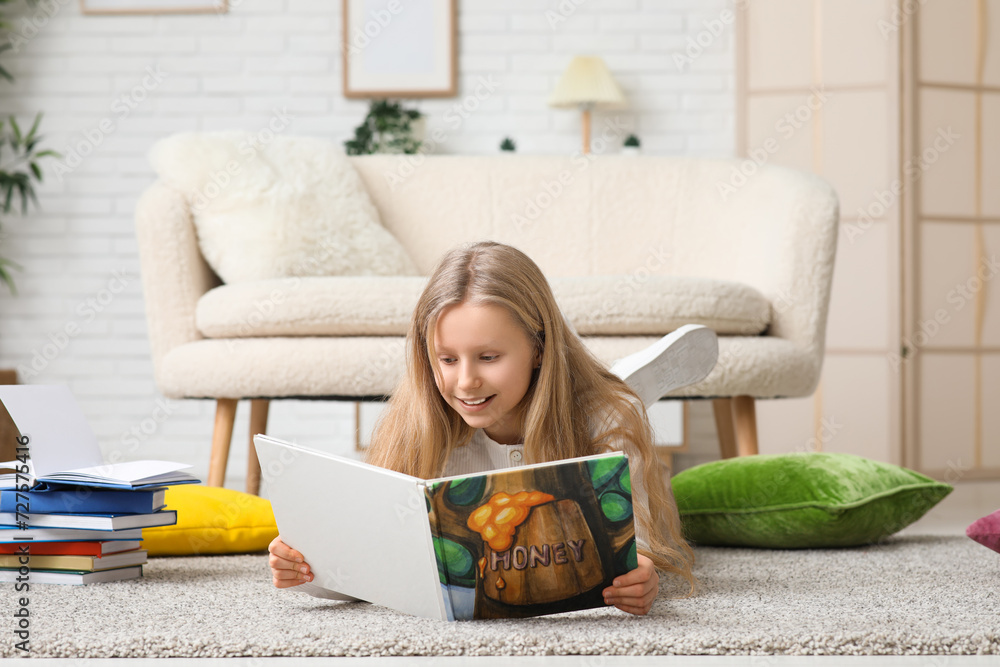 Little girl reading book on floor at home