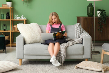 Sticker - Shocked little girl reading book on sofa at home