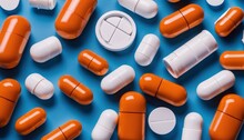 A Bunch Of Orange And White Pills On A Blue Background