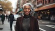 © Adriana - Attractive smiling white haired black mature woman posing in a city street looking at the camera