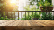 Leere Holztischplatte auf Balkon mit Blick auf Pflanzen in Blumentöpfen und Balkongeländer im warmen Sonnenlicht - Produktpräsentation - Urbane Oase
