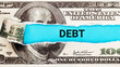 Debt. The word Debt in the background of the US dollar. Financial Burden, Loan, and Credit Concept. Stress from Financial Obligations.