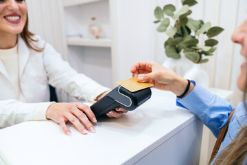 Close-up view of a client's hand as she uses a payment card on a terminal, symbolizing convenient technology at the clinic.