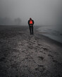 Hombre solitario andando por la arena de una playa en un día nublado 