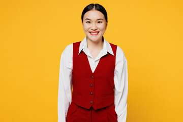 Wall Mural - Young cheerful happy corporate lawyer employee business woman of Asian ethnicity she wears formal red vest shirt work at office look camera isolated on plain yellow background studio. Career concept.