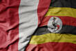 big waving national colorful flag of uganda and national flag of peru .