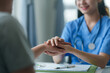 © amnaj - Caring nurse holding a patient's hand, providing comfort and support during a medical consultation.