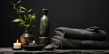 A Serene Scene Featuring A Towel Resting On Fern Leaves, Accompanied By Flickering Candles And Black Hot Stones, Evoking Tranquility And Relaxation.