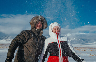 Sticker - Portrait of young happy couple of tourists on mountains background in winter with falling snow