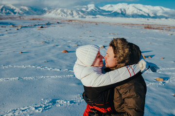 Wall Mural - Romantic young couple embracing on mountains background in winter