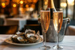 Champagne glasses with sparkling wine and bottle in bucket near oysters at restaurant