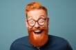 © Oleg Kozlovskiy - A man with a vivid red beard and stylish glasses radiates joy and personality, with a wide, infectious smile against a cool blue background