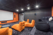 © alhim - Modern home theater design with gray wall and floor decor. A huge screen, a gray sofa and orange armchairs.