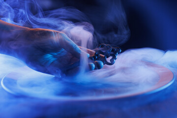 Wall Mural - Hand with a mysterious key in a bowl of magic liquid. Colored smoke moves beautifully against on a dark background. Fortune teller, mind power, prediction, halloween concept. Secret knowledge.