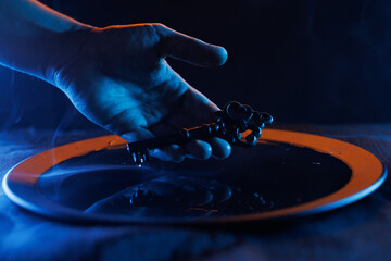 Wall Mural - Hand with a mysterious key in a bowl of magic liquid. Colored smoke moves beautifully against on a dark background. Fortune teller, mind power, prediction, halloween concept. Secret knowledge.