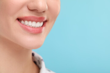 Poster - Woman with clean teeth smiling on light blue background, closeup. Space for text